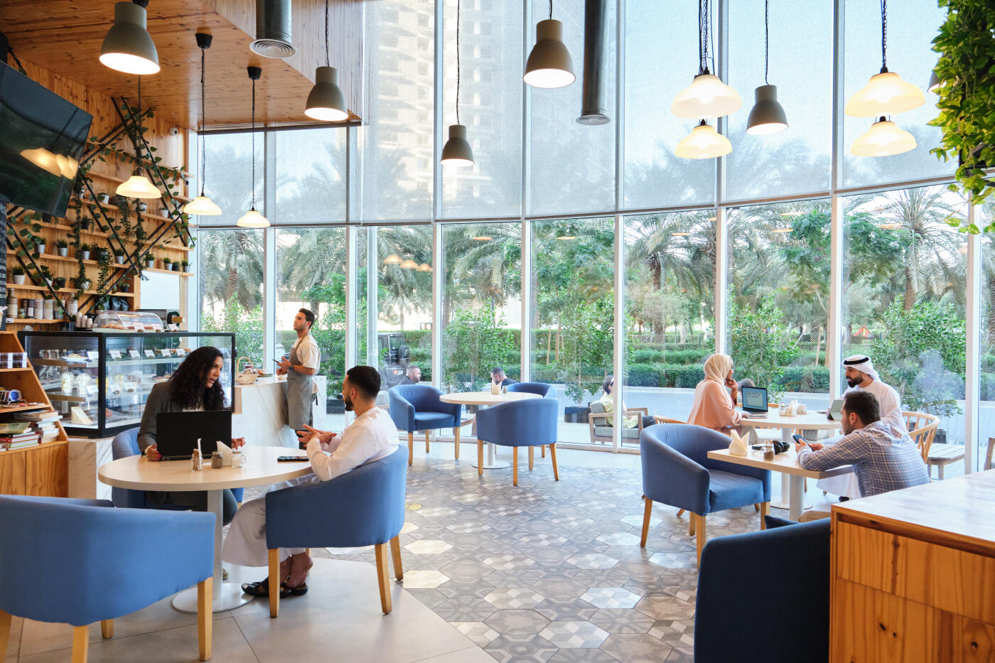 Customers sitting on chairs in coffee shop. Men and women are talking with each other. Interior of busy cafe.