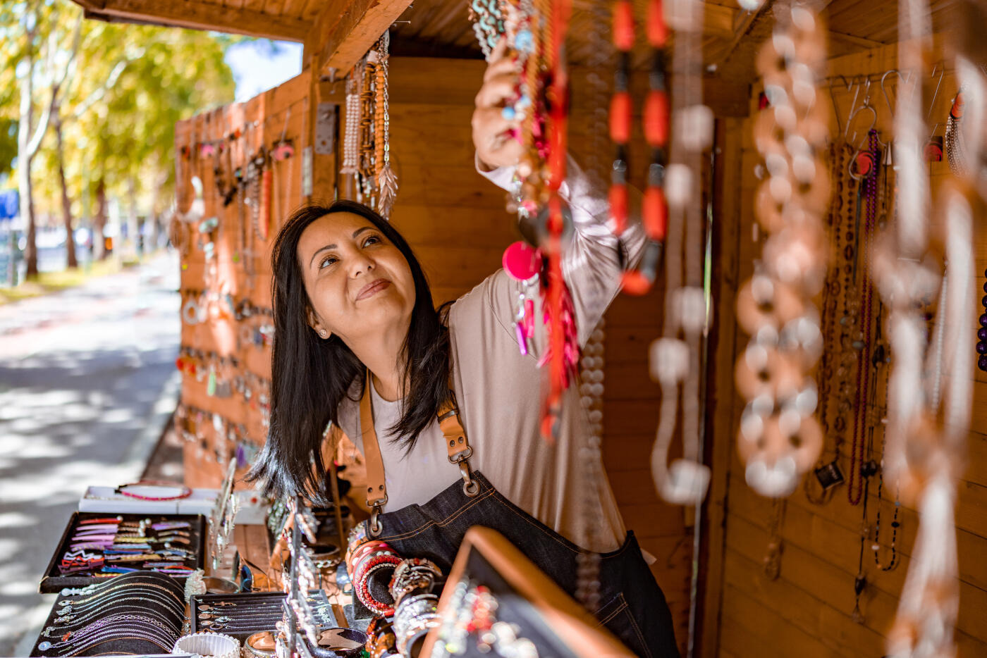 Mature jewelry maker adjusting her designs at her market stand