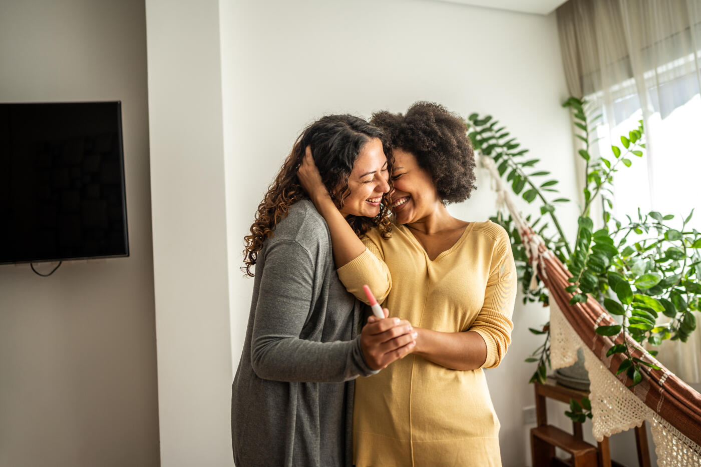 Lesbian couple holding a pregnancy test at home