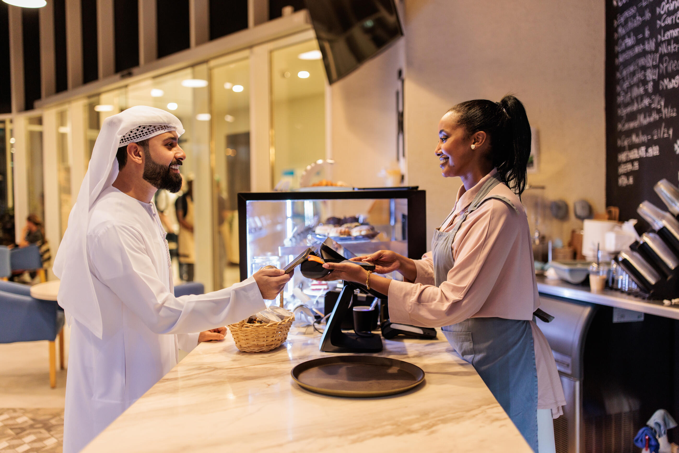 Ein arabischer Kunde beim kontaktlosen Bezahlen in einem Café in Dubai