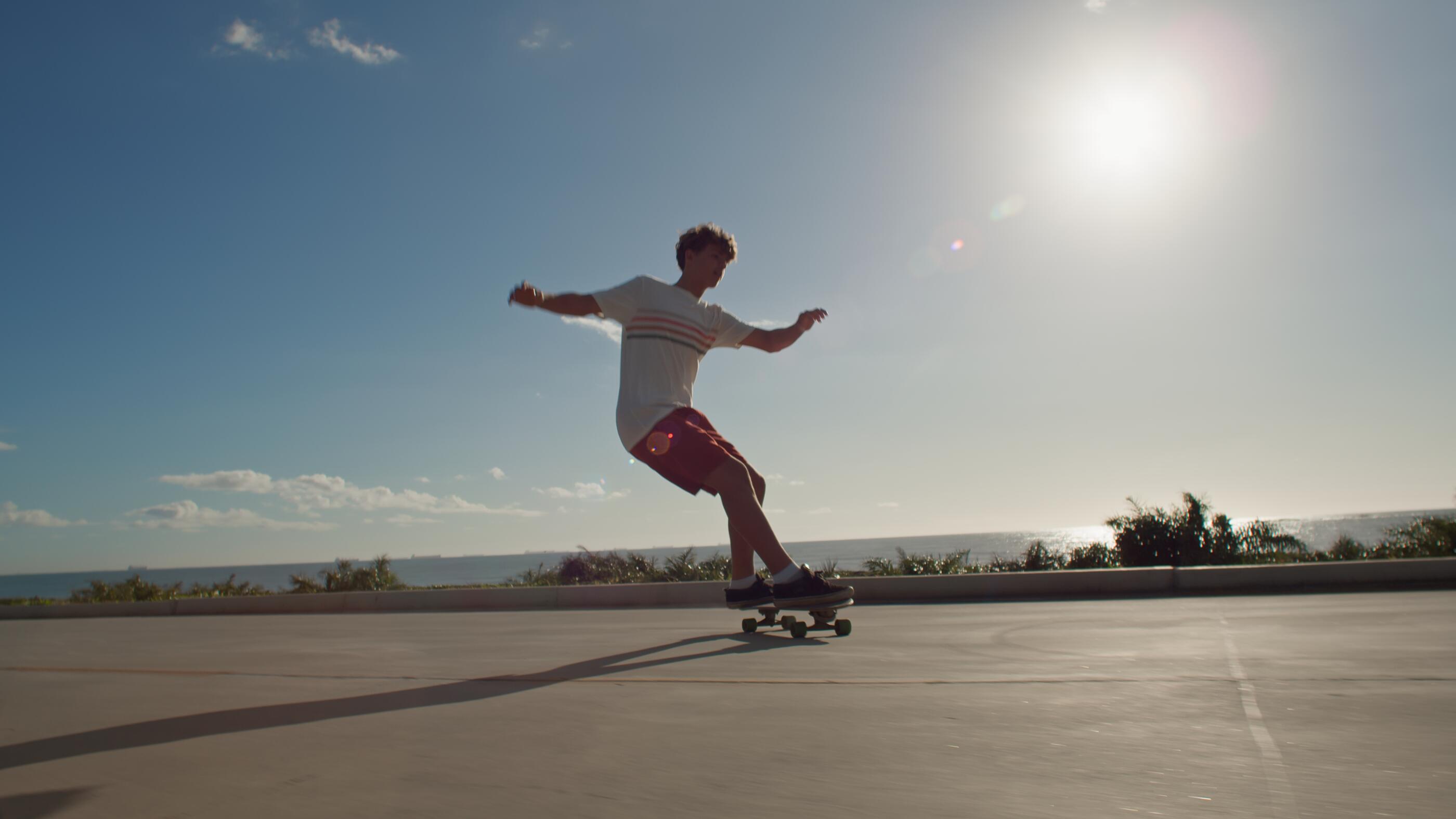 A young man longboarding at a boardwalk