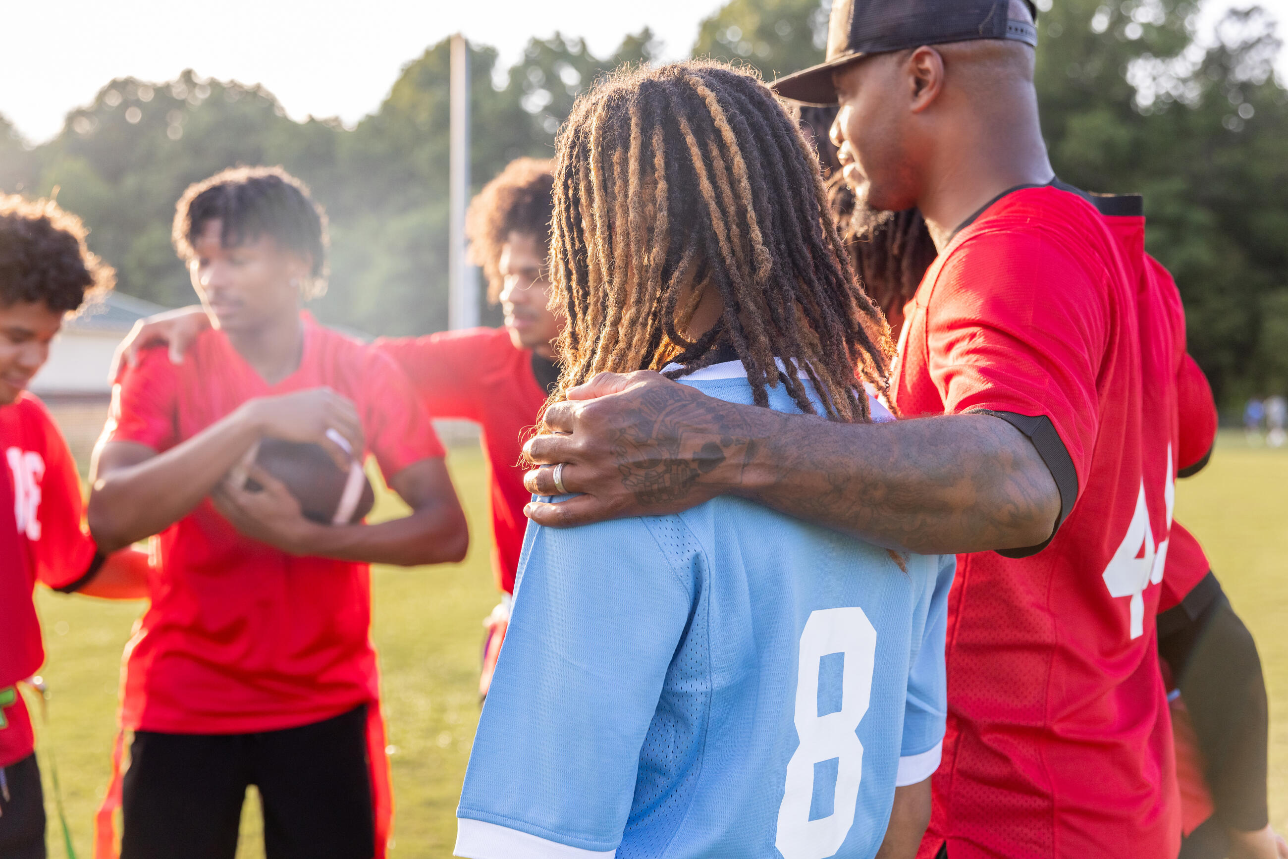 Der Coach im Huddle mit dem High-School-Flag-Footballteam am Rand des Spielfelds