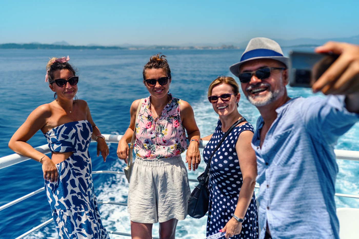 Group of friends on the ferry boat deck on a sunny day traveling on vacation