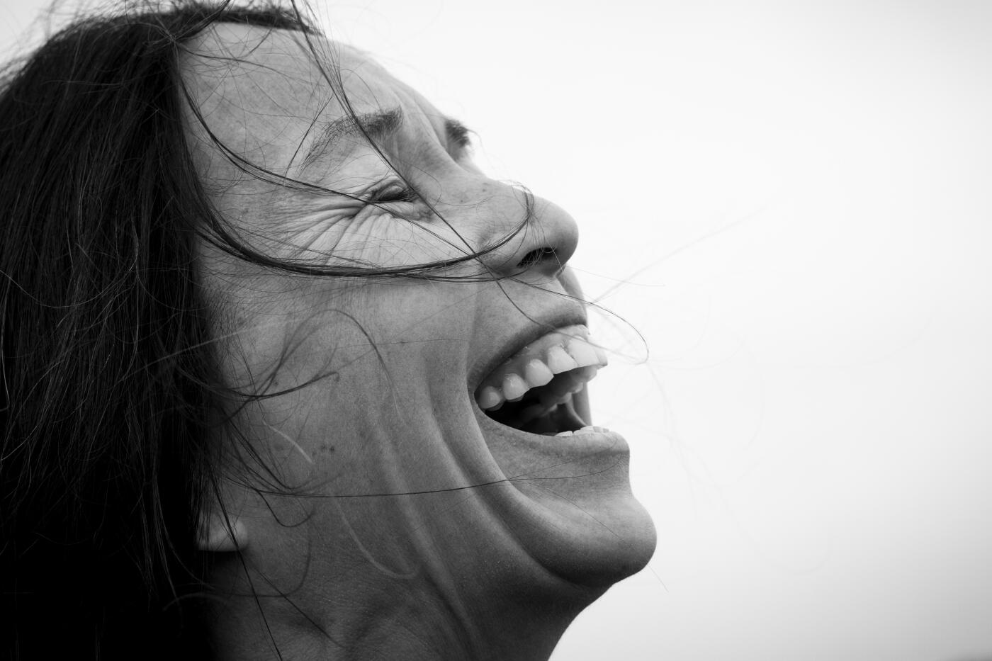 Side view headshotof laughing woman with black hair