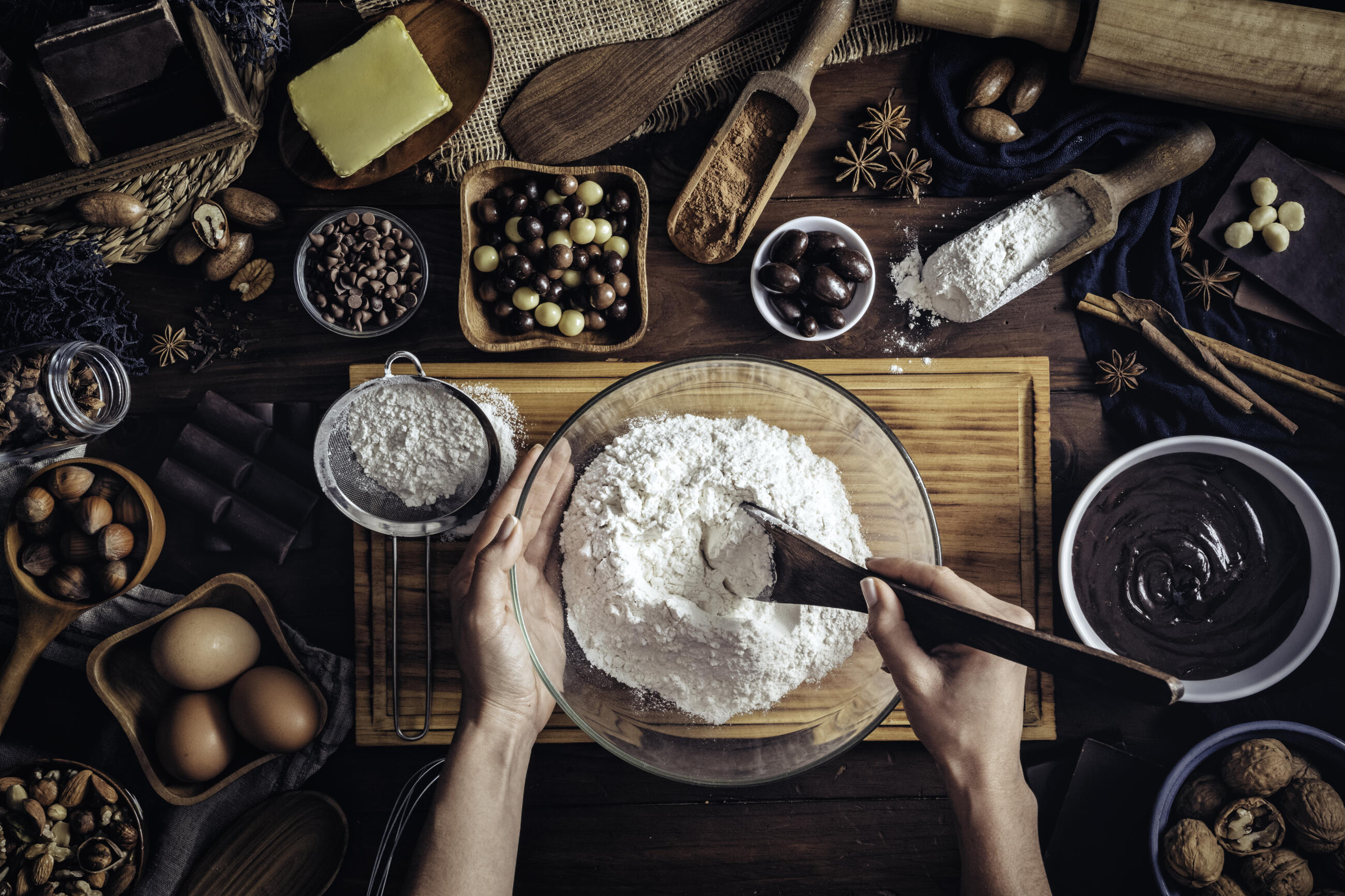 Woman hands making chocolate mousse and cookies on a wooden table in a rustic kitchen