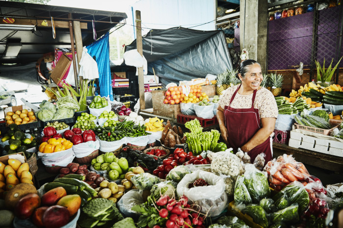 Laughing female produce vendor working at stand in marketplace