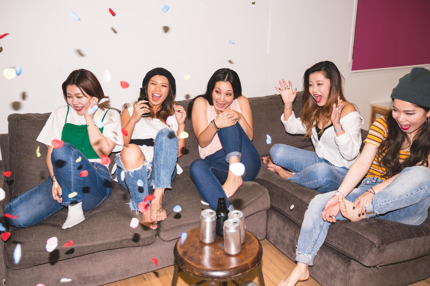 Five young woman drinking beer at a social event surprised by a party cracker