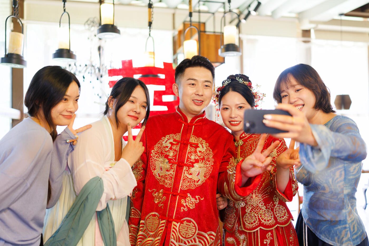 A Chinese newlywed couple in their 30s, wearing Hanfu costumes, are taking a photo with friends who come to congratulate them on their wedding day.