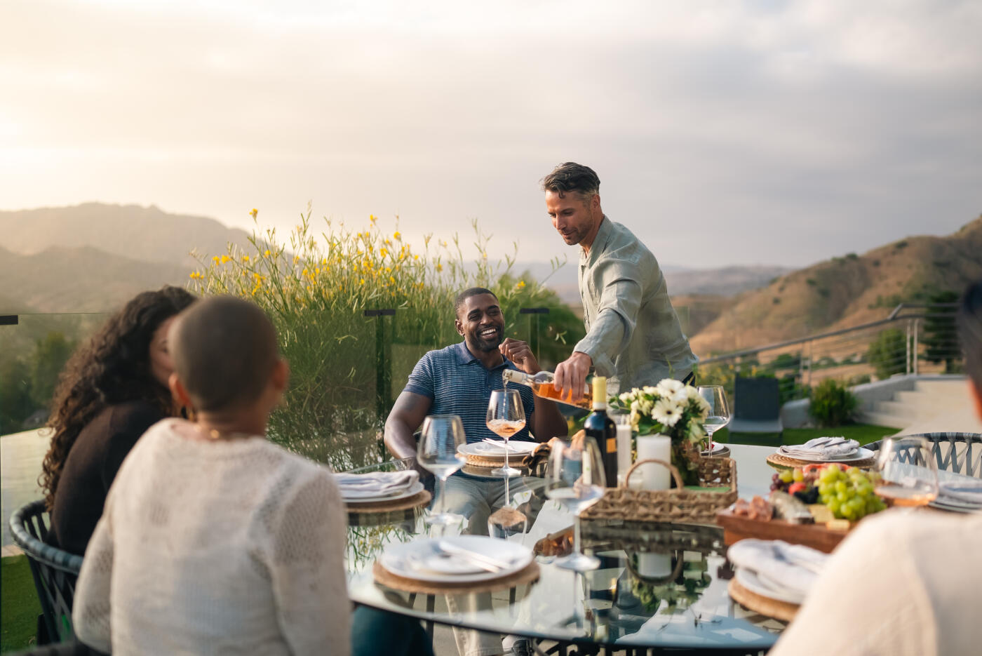 A diverse group of friends shares food, conversation, and laughter while dining together in the sophisticated dining room of a high-end home. The scene captures friendship, celebration, upscale living, and meaningful social connection.
