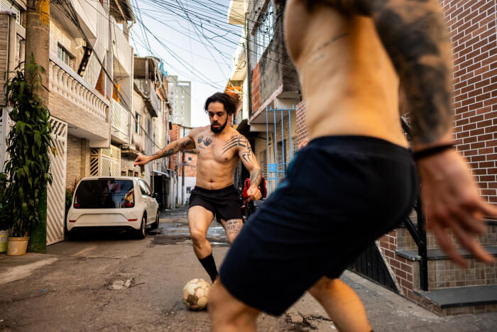 Friends playing soccer on a street in São Paulo, Brazil