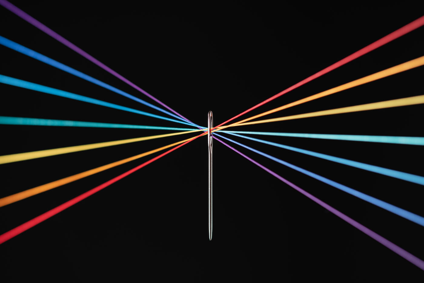 Crossed Rainbow Colored Strings Converge Through Needle Eyelet on Black Background Macrophotography, Selective Focus.