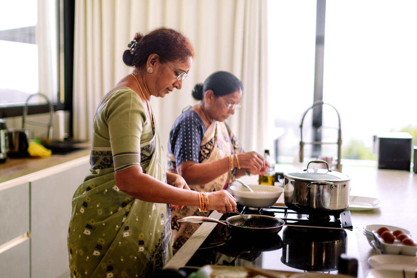 Adult woman cooking alongside her senior mother while preparing a traditional family recipe in a home kitchen