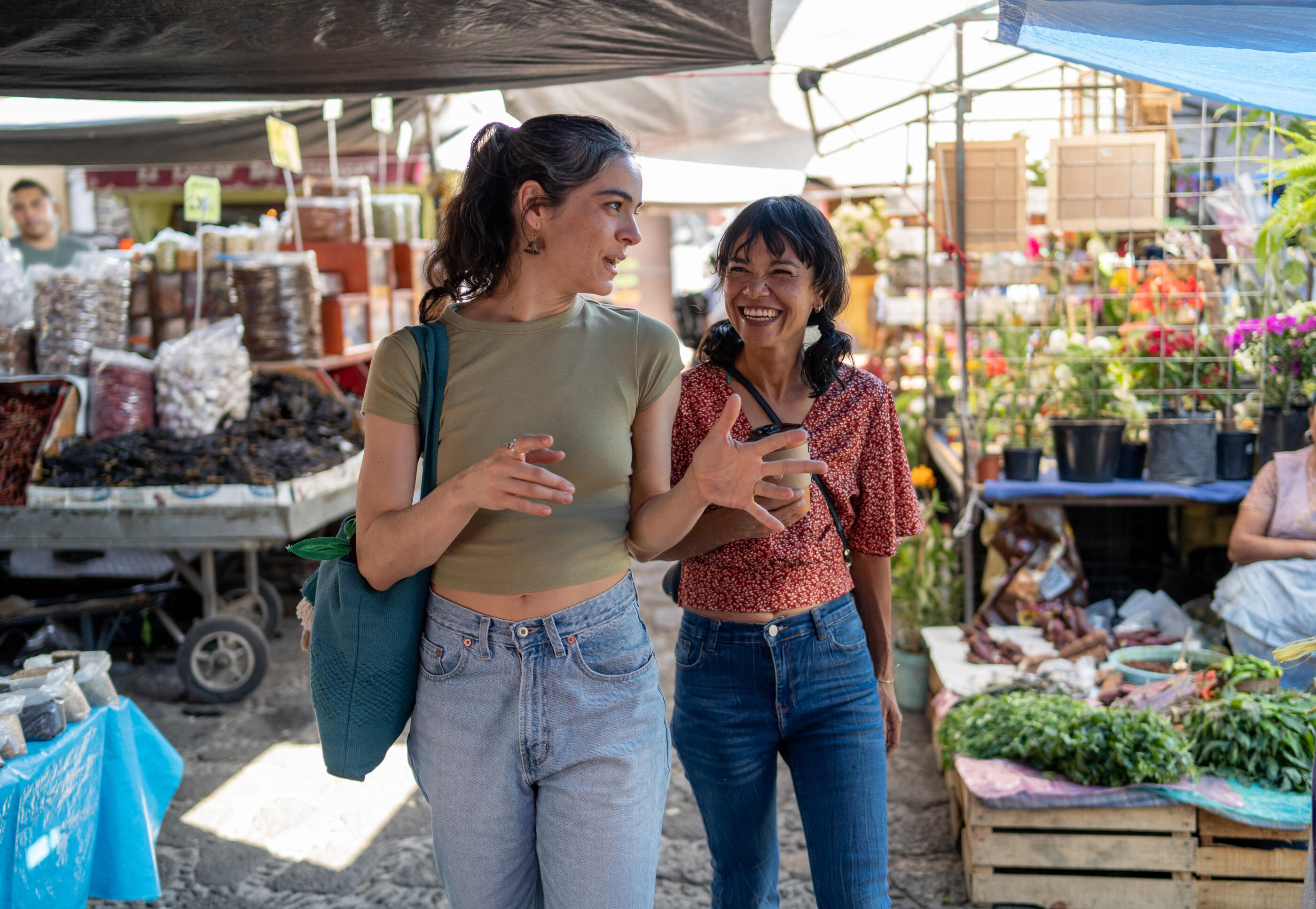 two women friends walking through market stalls at an outdoor street market in mexico