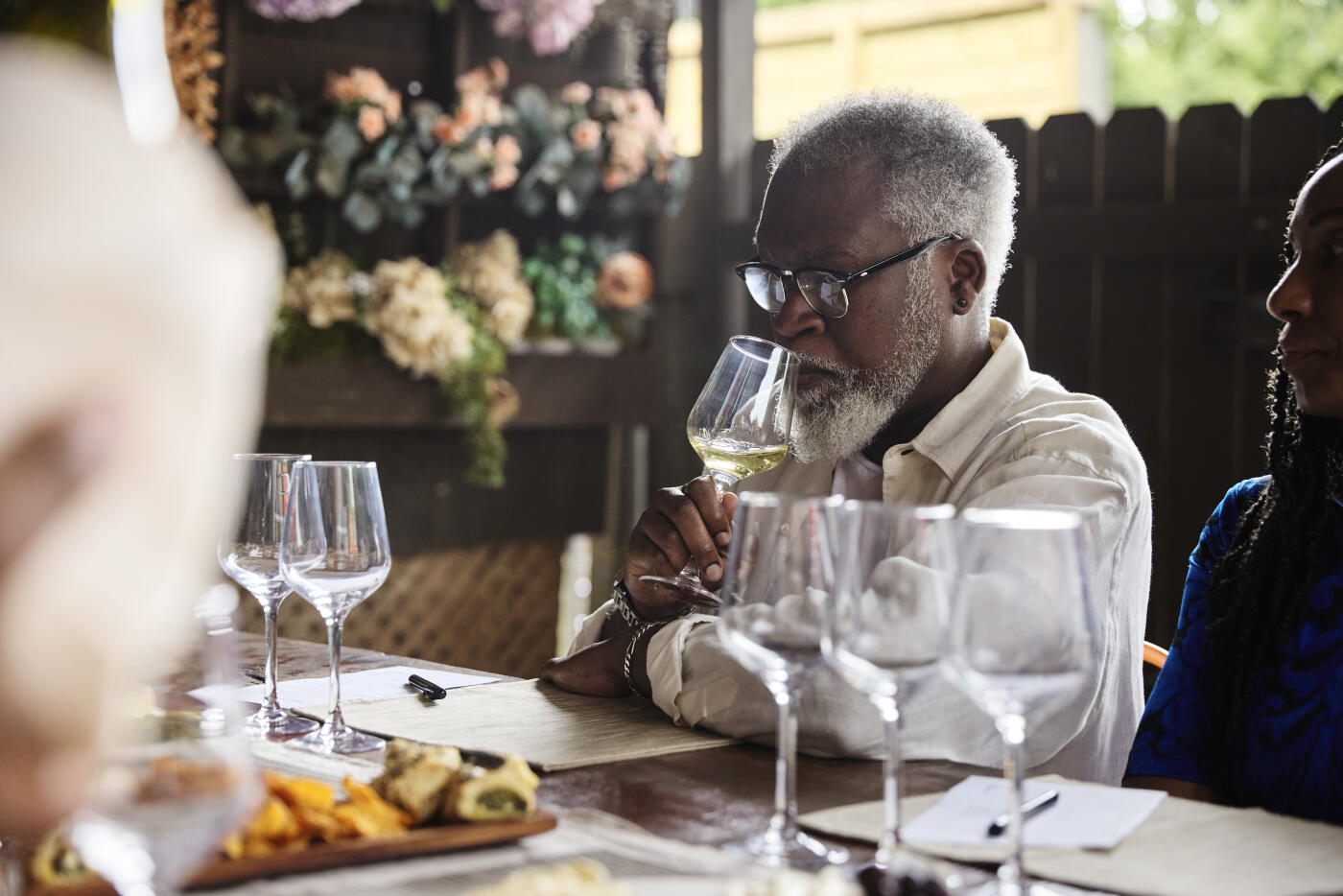 Mature man savoring wine notes during a wine tasting dinner with friends.