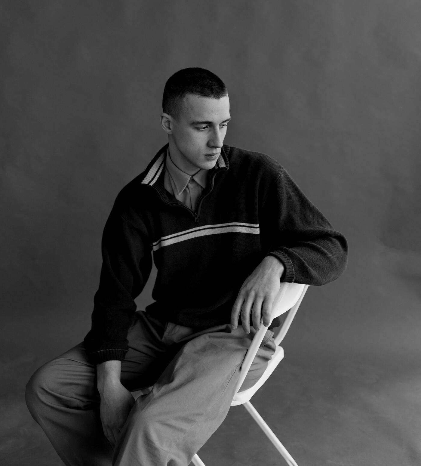 Black and white portrait of a young man sitting in the studio