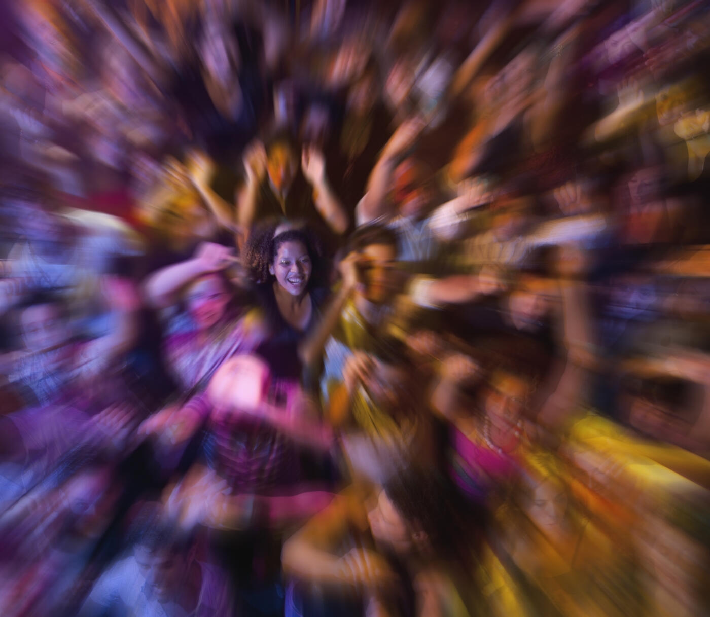 A concert or club scene filled with dancing people, vibrant color, and a zoom effect centering on one celebrating woman.