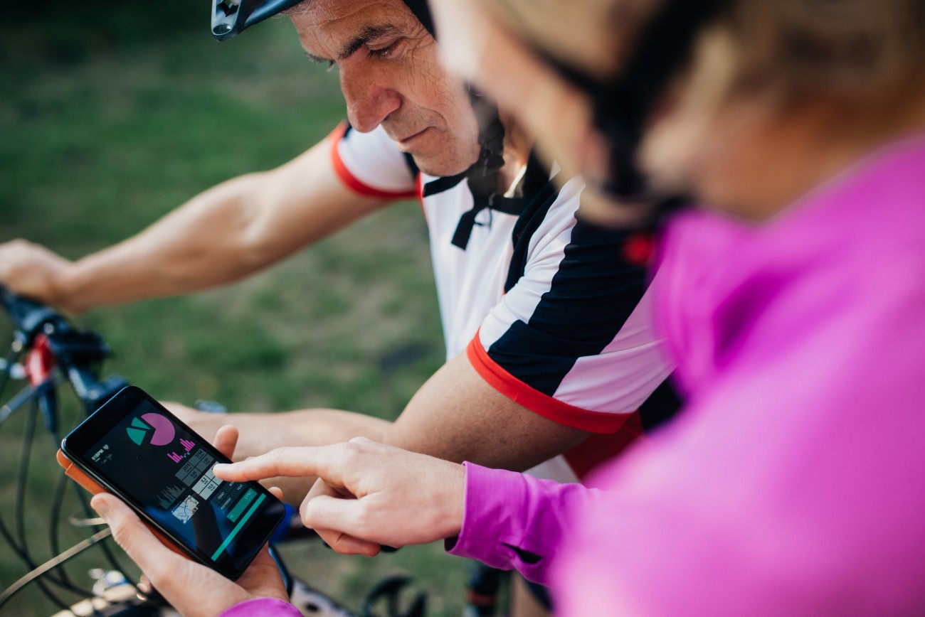 Mature couple checking tracking app with smartphone after biking trip.