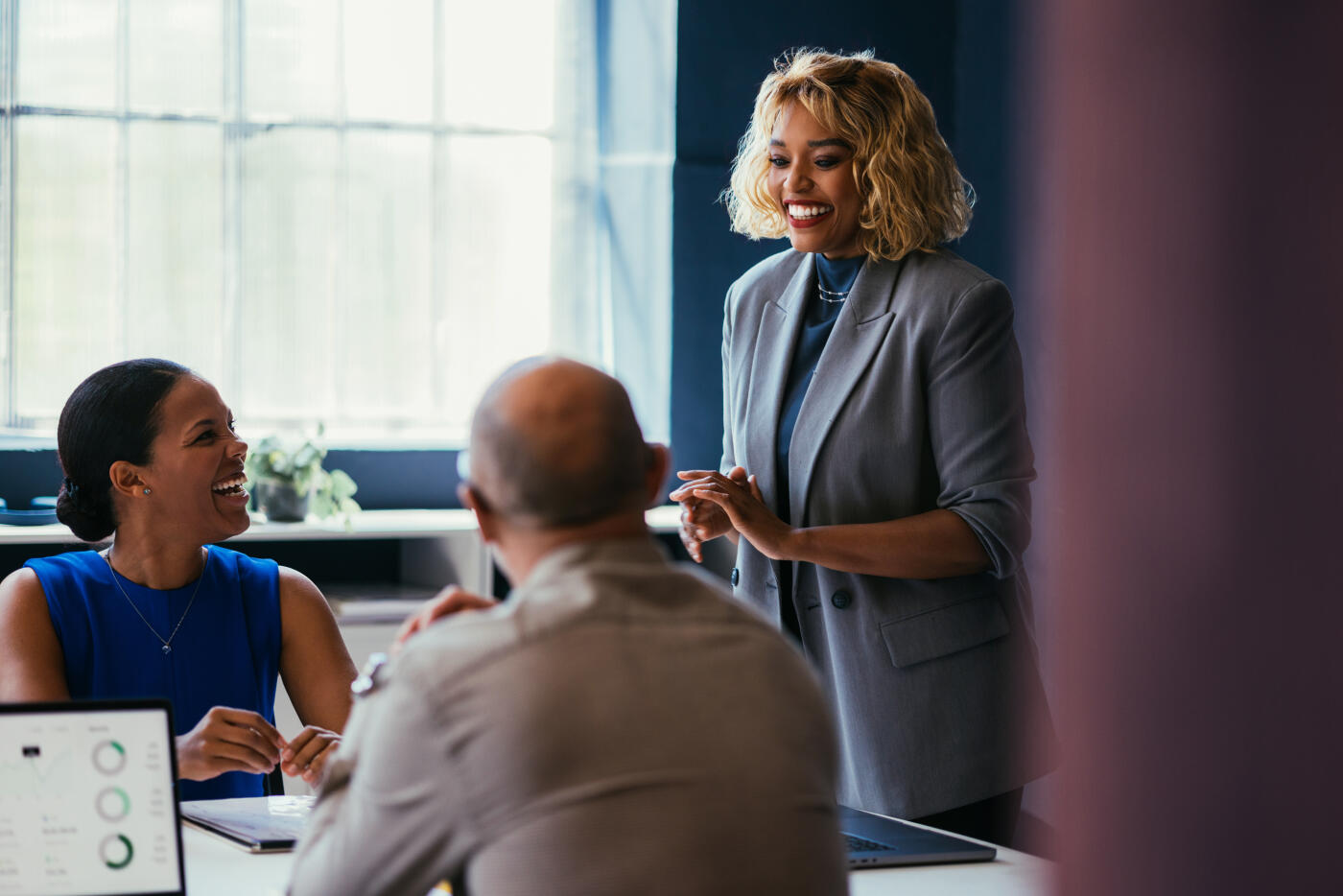 A diverse group of business professionals engaged in a collaborative meeting, sharing ideas and laughter, in a well-lit modern office. This image captures teamwork, positivity, and professional interaction.