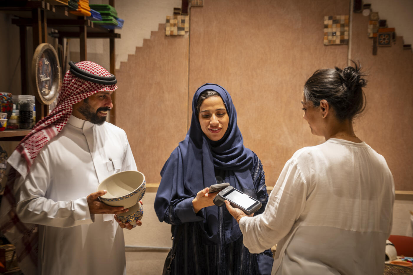 Saudi couple shopping together in Souq Al-Alawi making contactless mobile payment with phone