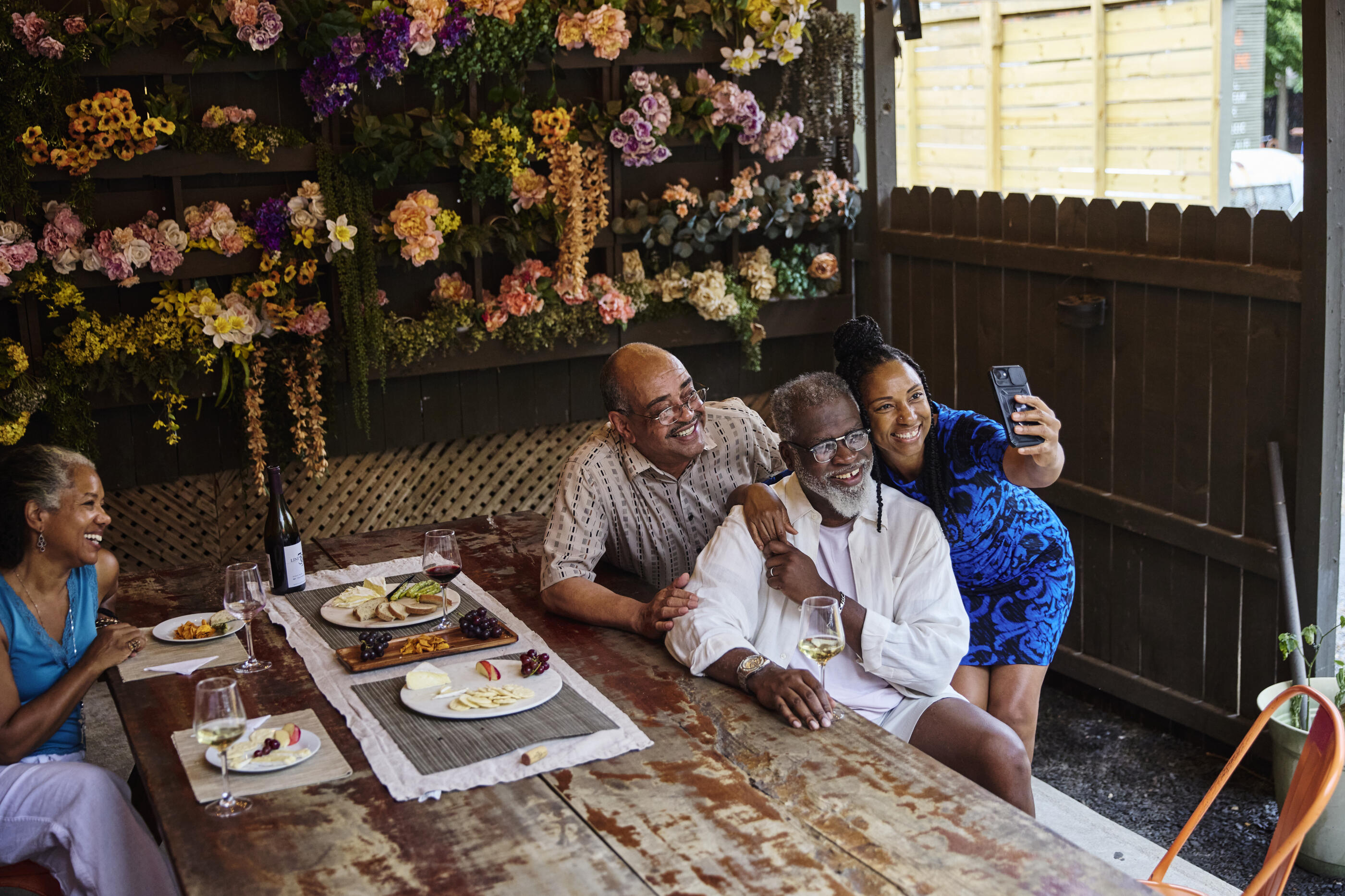 Smiling mature woman taking selfie with friends in restaurant