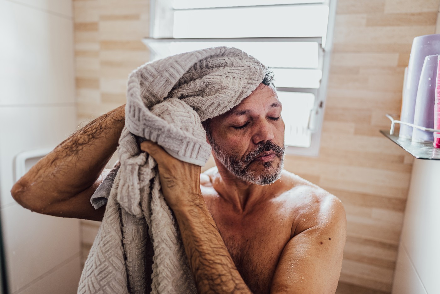 Mature gay man drying off after a shower in the bathroom