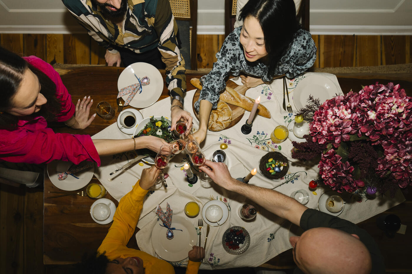 Landscape Format of a medium sized diverse group of friends sitting at a table toasting with champagne