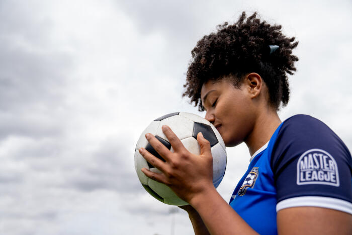 Profile view of a female soccer player kissing a ball