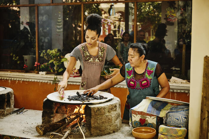 Medium wide shot of teacher assisting student in Mexican cooking class