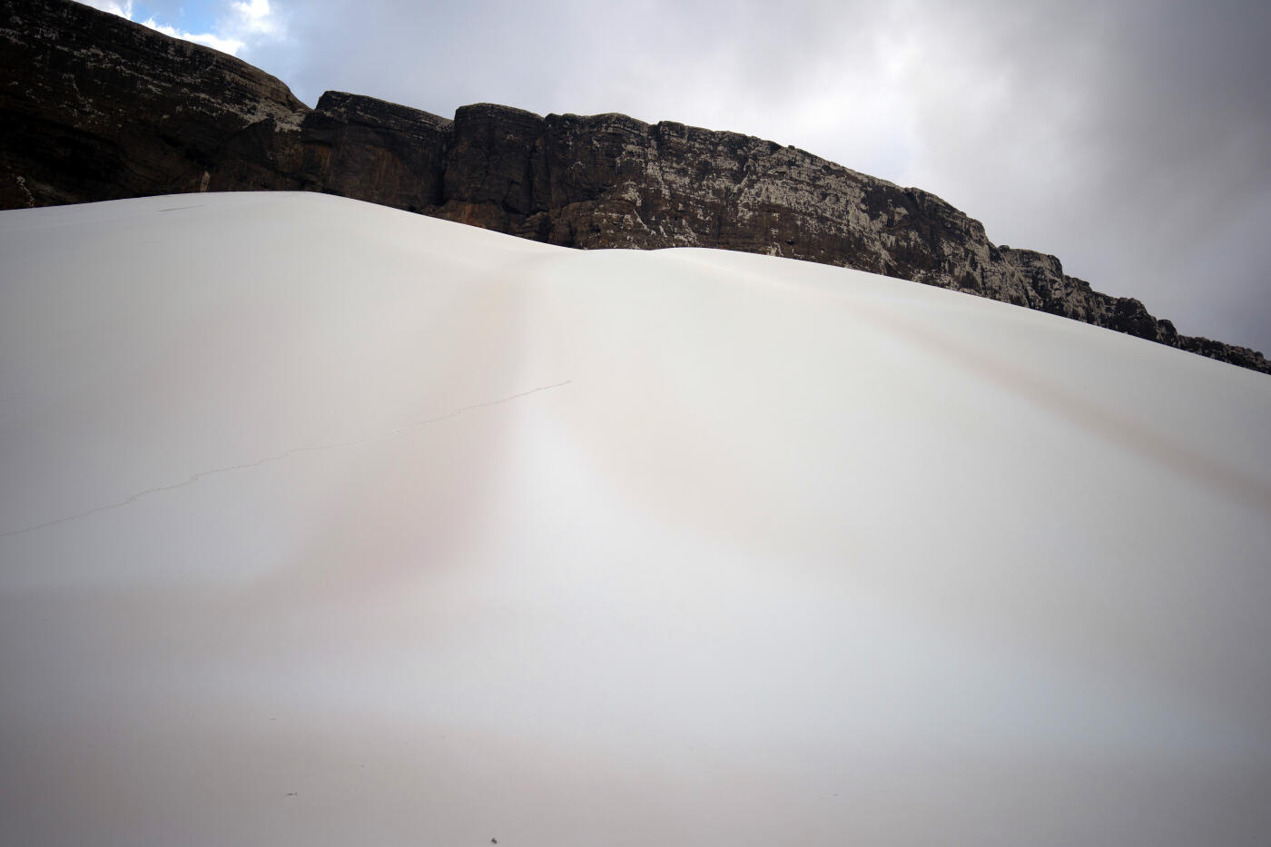 SOCOTRA ISLAND, YEMEN - OCTOBER 11: A giant sand dune pushes up against a cliff face on October 11, 2025 in Socotra, Yemen. Socotra island, sometimes referred to as the "Galapagos Islands" of the Indian Ocean, lies about 150 miles off the coast of the Horn of Africa and is home to 825 plant species, more than a third of which are only found here. Among them are the otherworldly dragon's blood tree, bottle trees and 11 species of frankincense, 4 of which were classified as critically endangered in March of this year. The intensifying tropical cyclones in this part of the Indian Ocean, fuelled by climate change, has put the island's unique ecosystem at risk. Meanwhile, Yemen's civil war - as well as the region-destabilizing attacks on commercial vessels in the Red Sea - have complicated conservation efforts. (Photo by Carl Court/Getty Images)