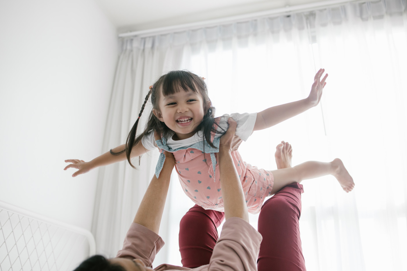 Thai grandmother and granddaughter playing together on the bed - Stock image