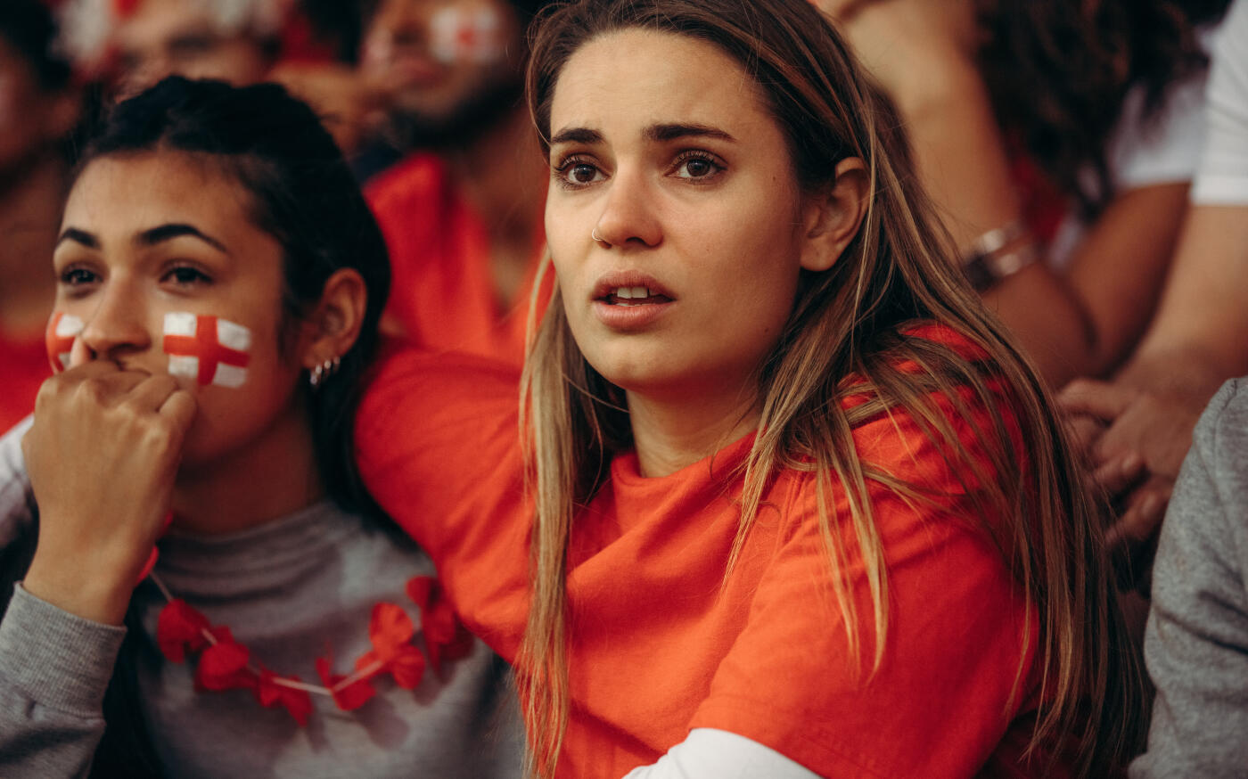 Anxious England team supporter watching a live match from stadium. English soccer fans in crowd looking upset during game.