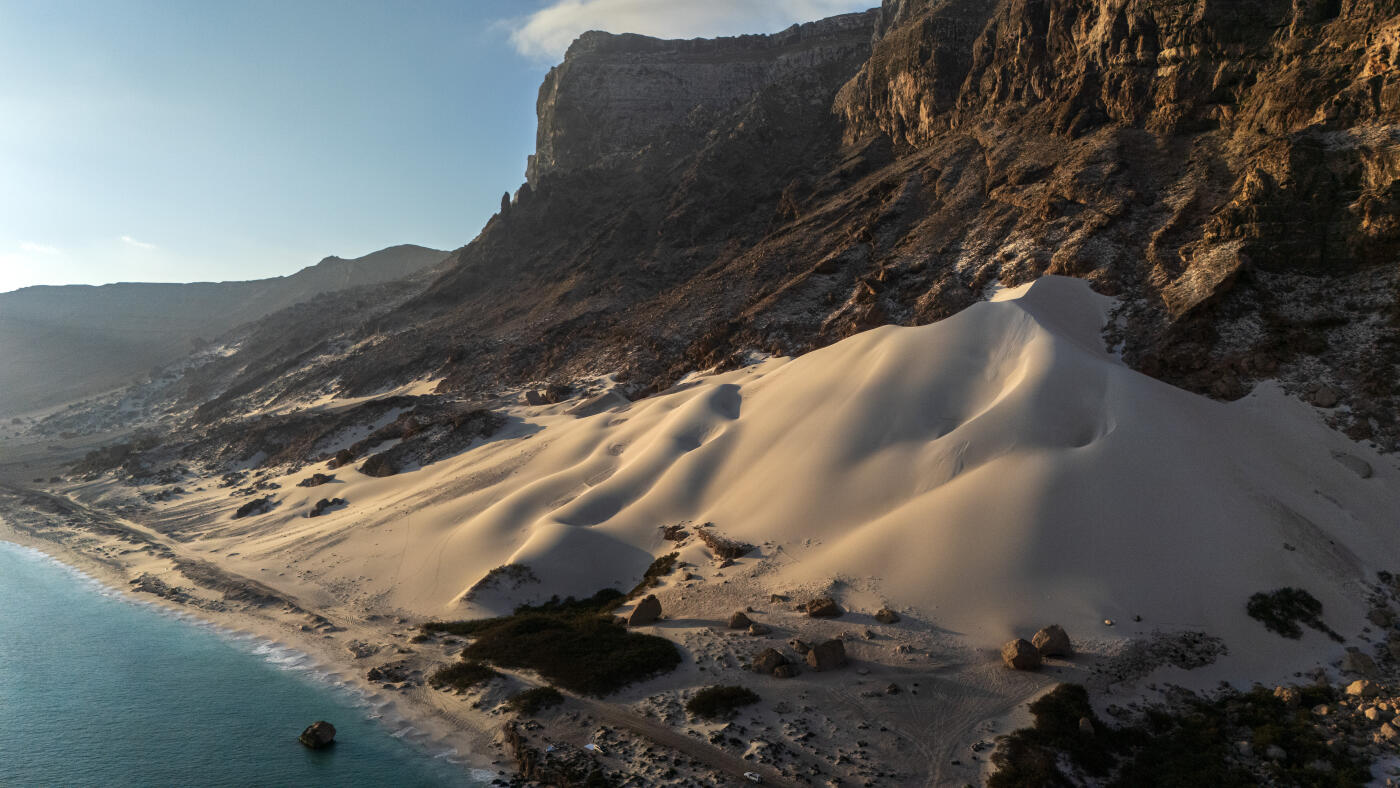 SOCOTRA ISLAND, YEMEN - OCTOBER 12: A giant sand dune pushes up against a cliff on October 12, 2025 in Socotra, Yemen. Socotra island, sometimes referred to as the "Galapagos Islands" of the Indian Ocean, lies about 150 miles off the coast of the Horn of Africa and is home to 825 plant species, more than a third of which are only found here. Among them are the otherworldly dragon's blood tree, bottle trees and 11 species of frankincense, 4 of which were classified as critically endangered in March of this year. The intensifying tropical cyclones in this part of the Indian Ocean, fuelled by climate change, has put the island's unique ecosystem at risk. Meanwhile, Yemen's civil war - as well as the region-destabilizing attacks on commercial vessels in the Red Sea - have complicated conservation efforts. (Photo by Carl Court/Getty Images)