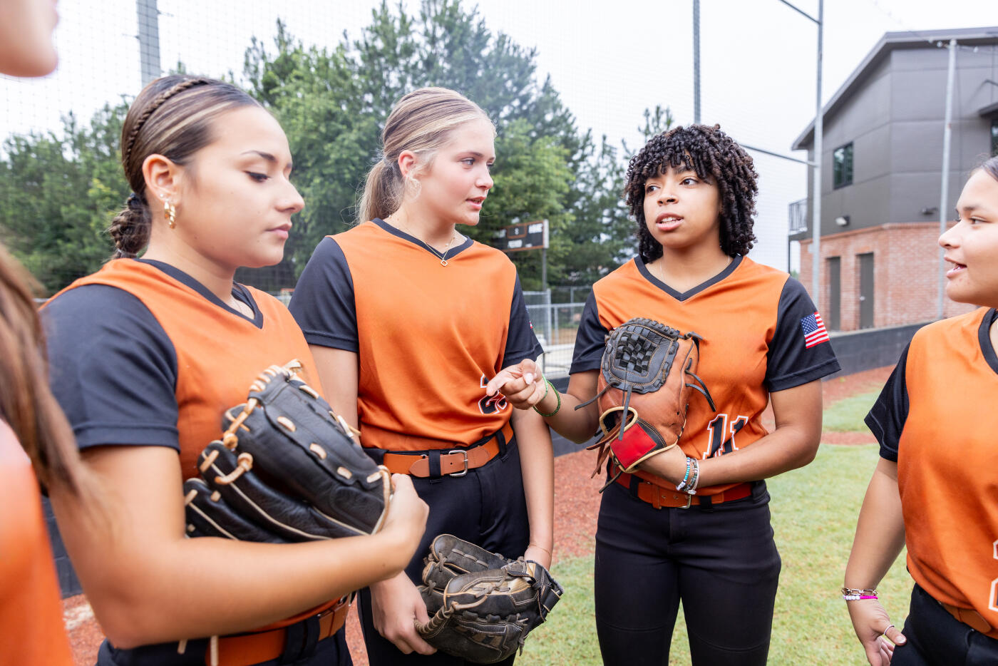 Teen girls stand in huddle with softball teammates before taking the field to play a game