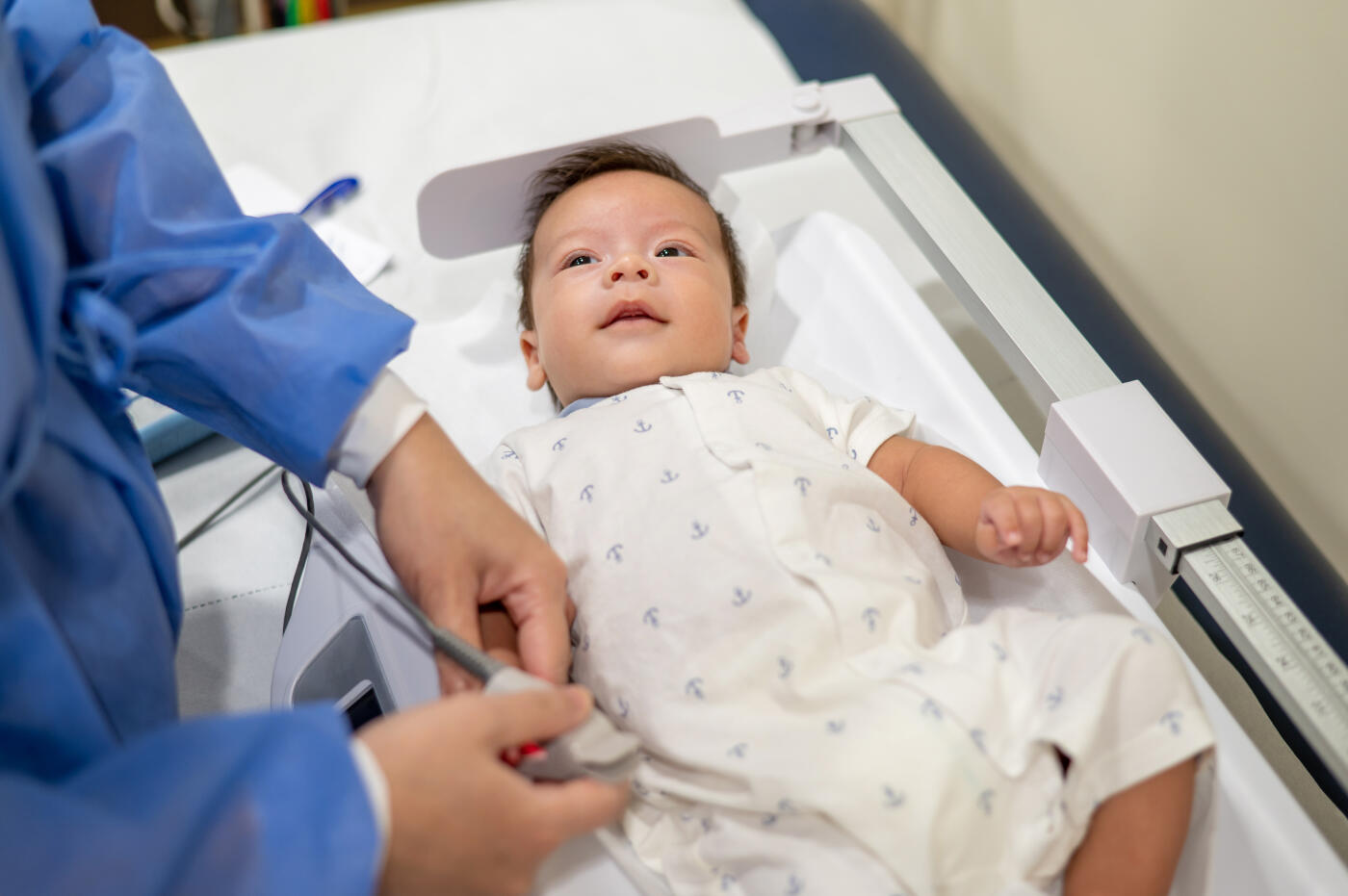 Doctor or a medical nurse checking newborn baby boy body vital signs as oxygen saturation with Pulse Oximeter during a routine newborn baby regular health checkup in a hospital