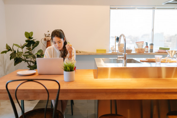 Young woman using laptop while having breakfast at home