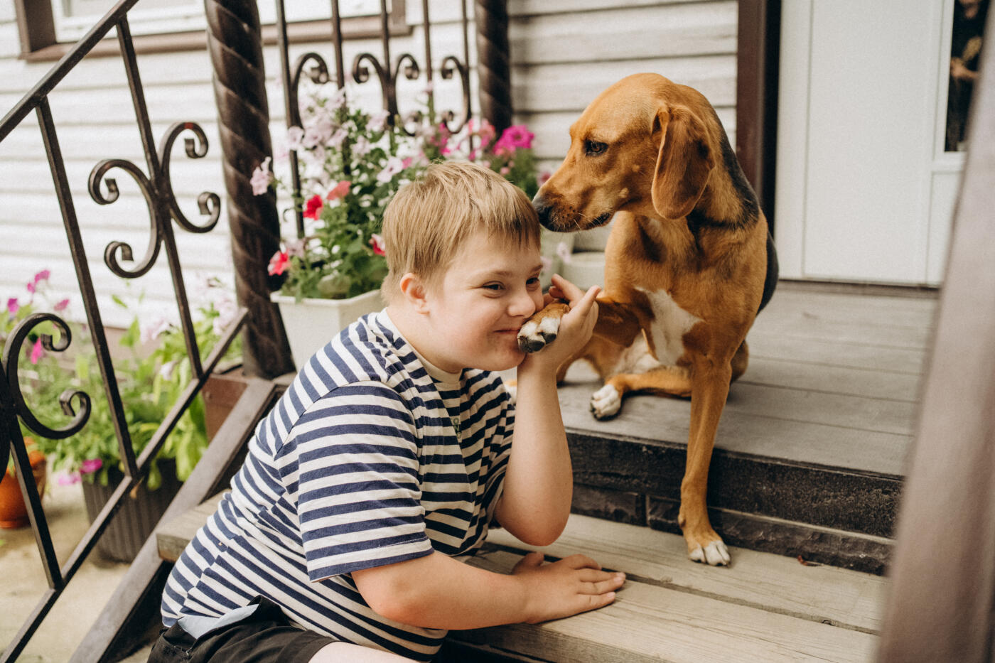 Heartwarming scene of a boy with down syndrome gently holding his dog's paw, showcasing the special bond between them