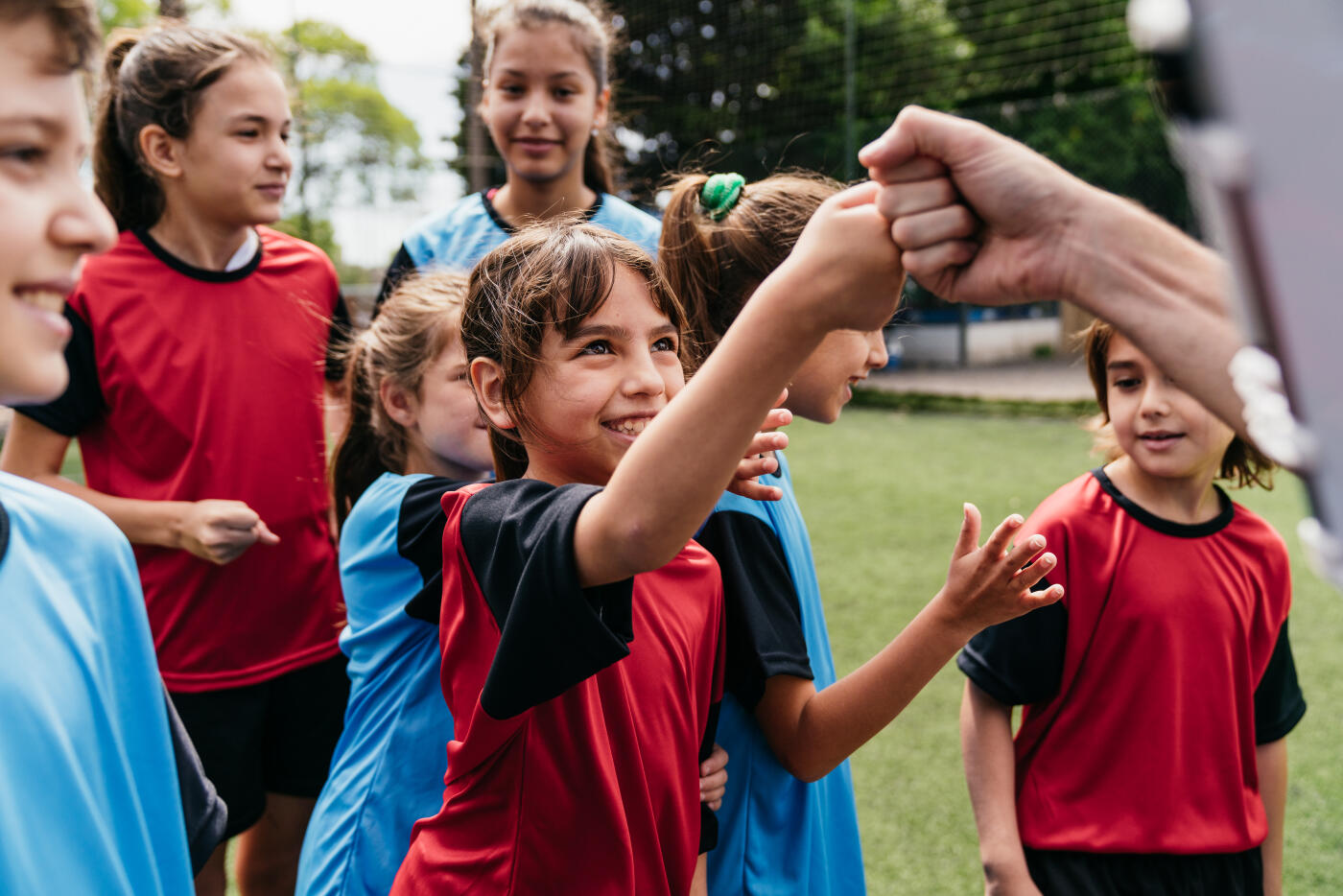Team of female and male kids together on a soccer field. They are greeting each other with a fist bump.