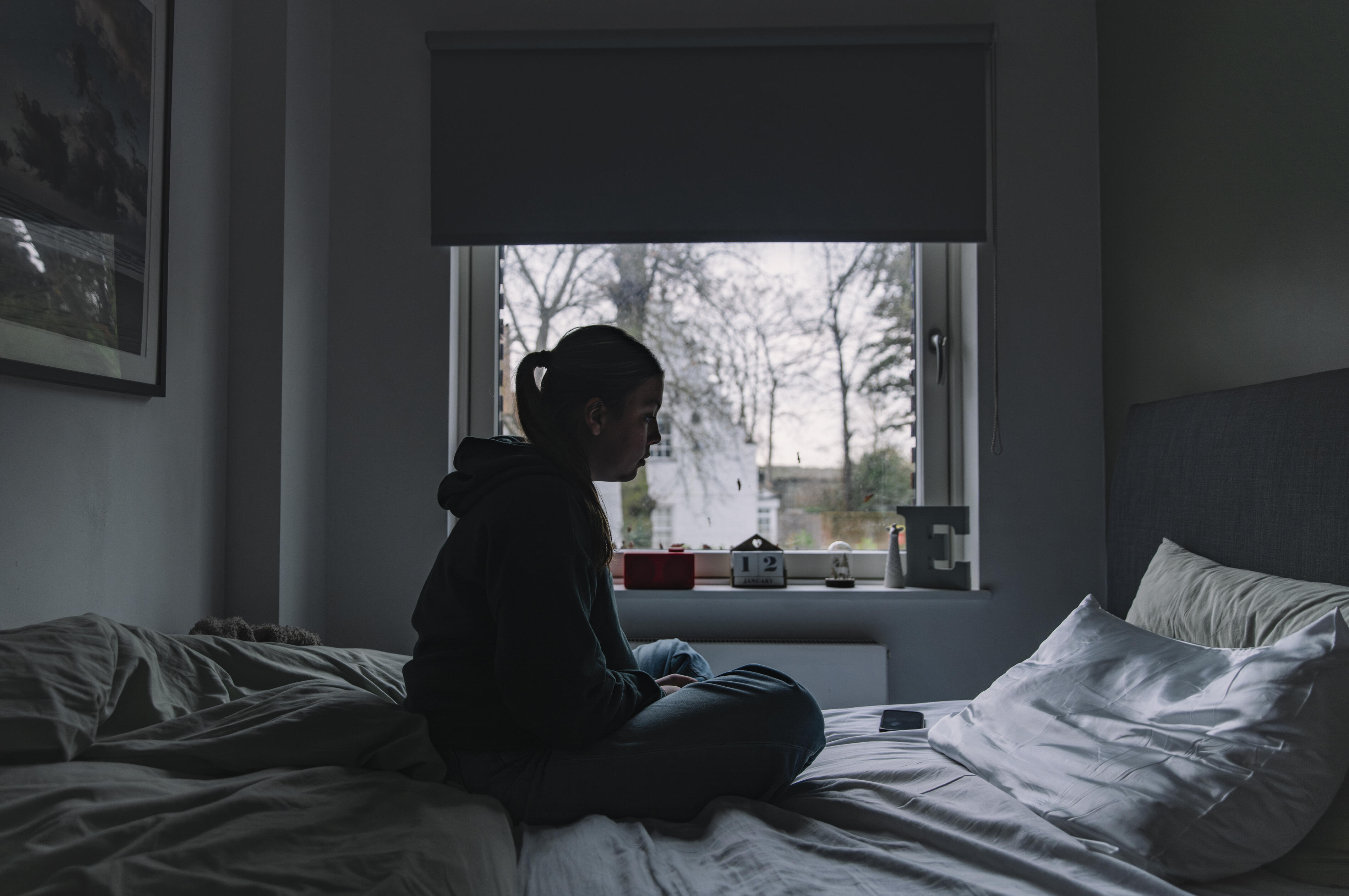 Shot of a young woman sitting on her bed - negative emotion