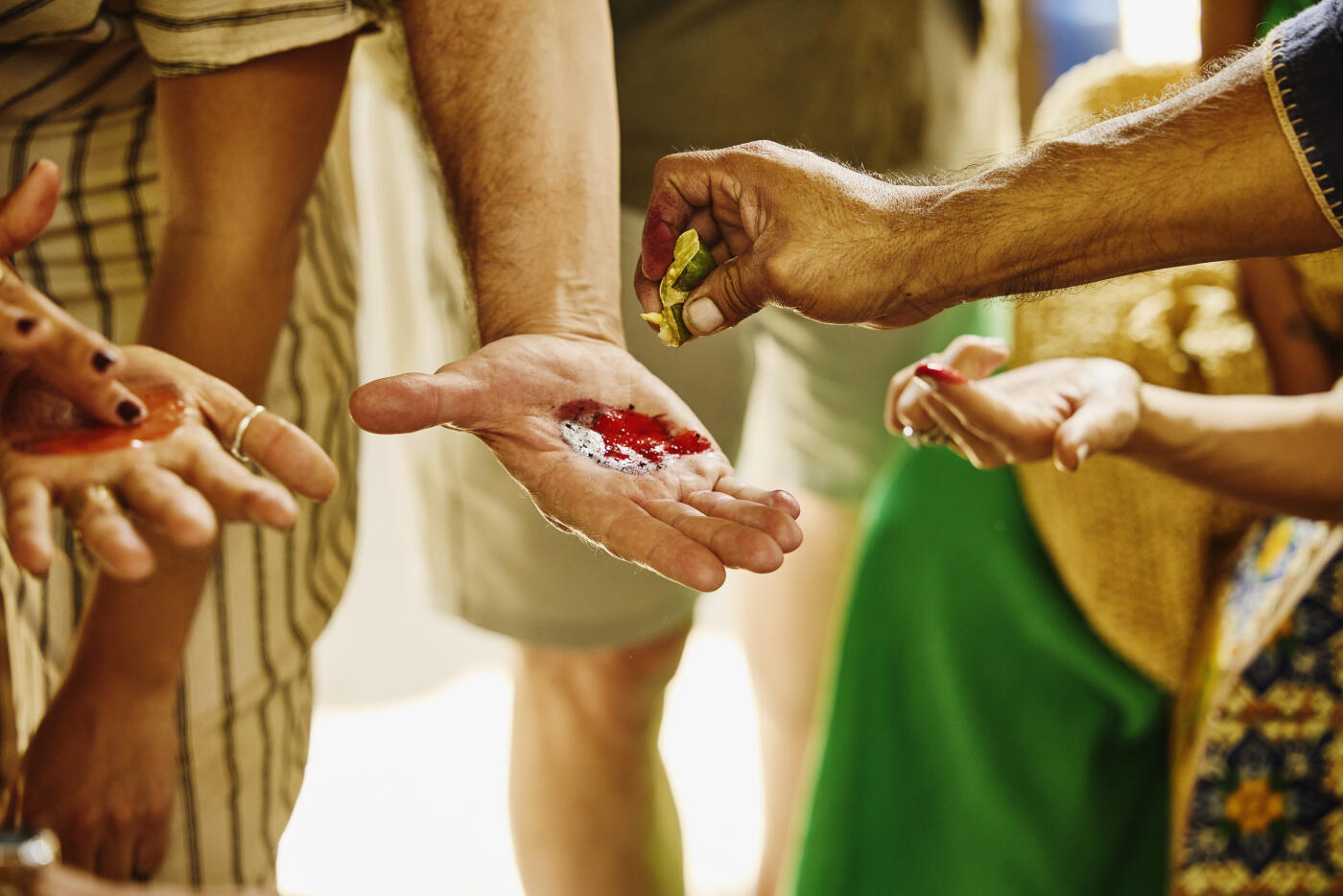 Medium close-up shot of artisan showing student natural dyeing technique involving mixing ingredient with lime juice during traditional textile workshop demonstration