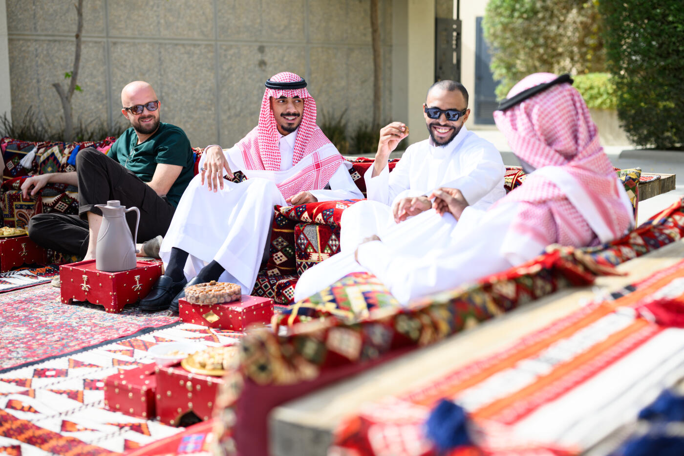 Middle Eastern men sitting on traditional cushions outdoors drinking tea