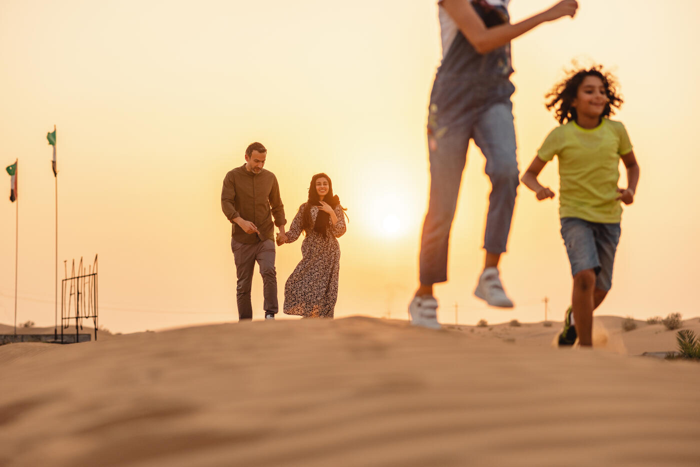 Young family outdoors in the desert having fun on their vacation in Dubai.