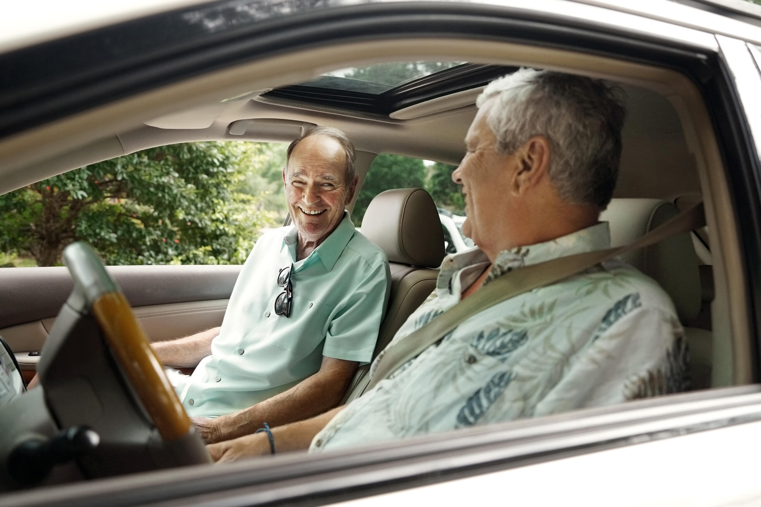 Zwei ältere Männer sitzen lächelnd im Auto, bevor sie losfahren