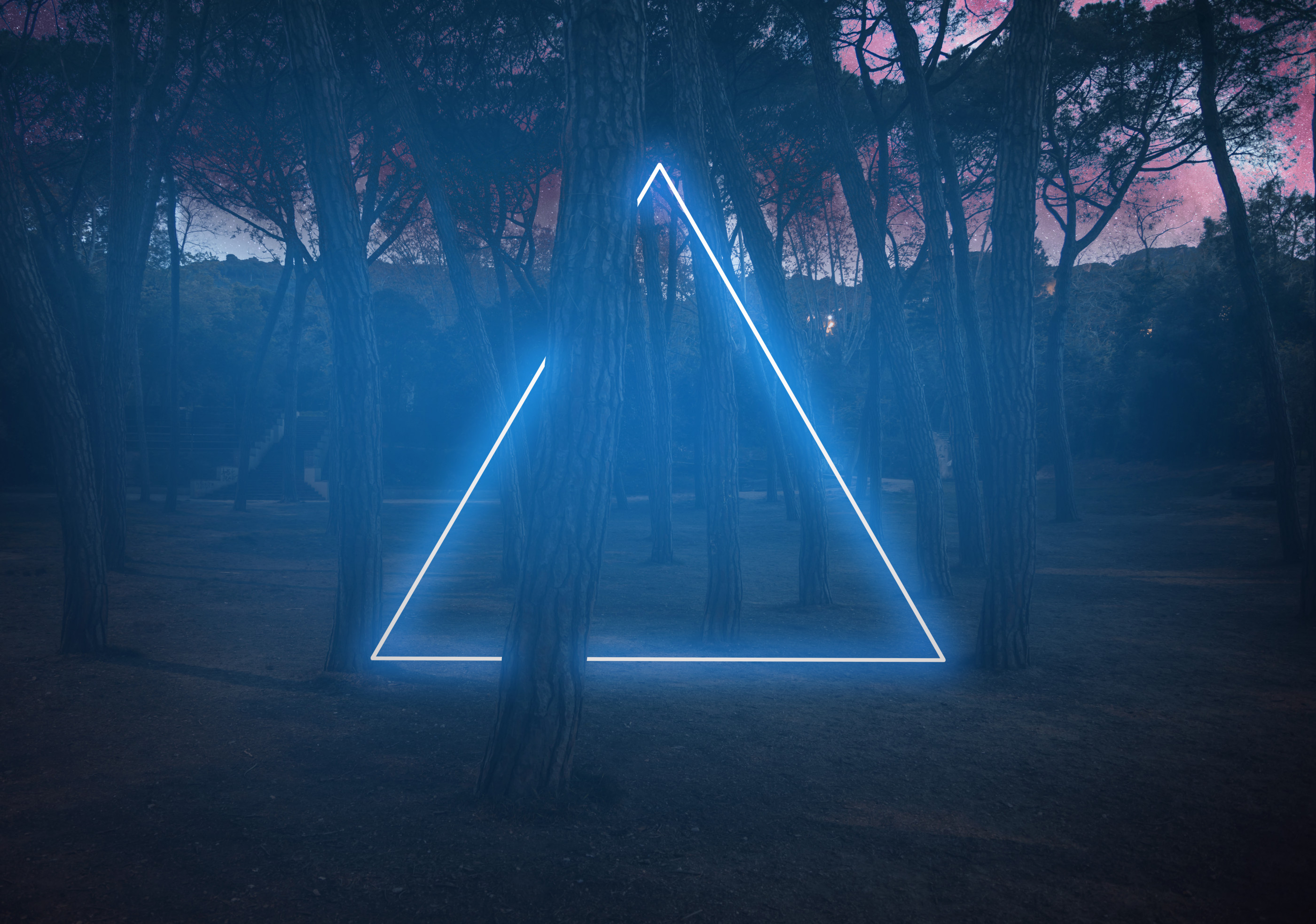 Blue neon triangle light between pine trees with futuristic visual effect.