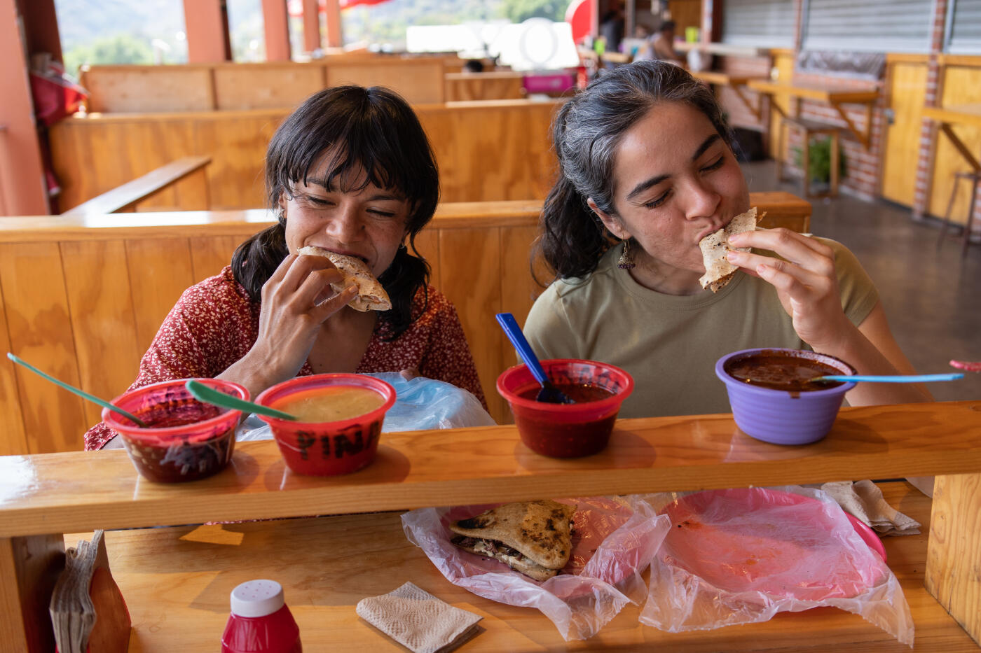 Two women friends trying street food at a food market in Tepoztlán, mexico
