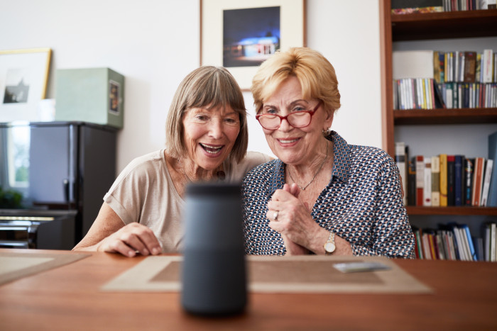 Excited senior friends using a smart speaker