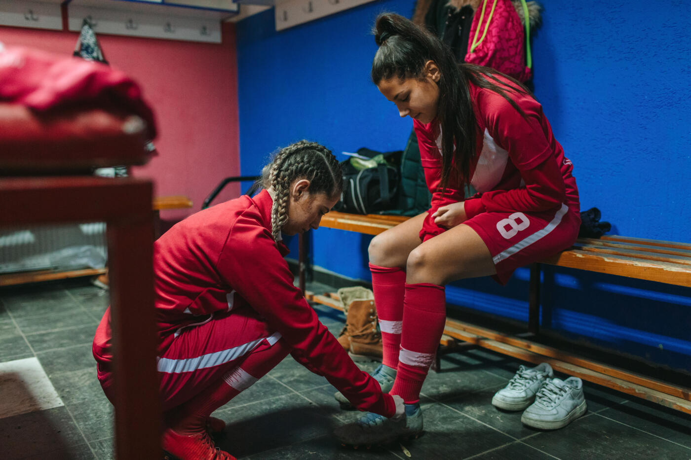 Female soccer player helping to her teammate in locker room.