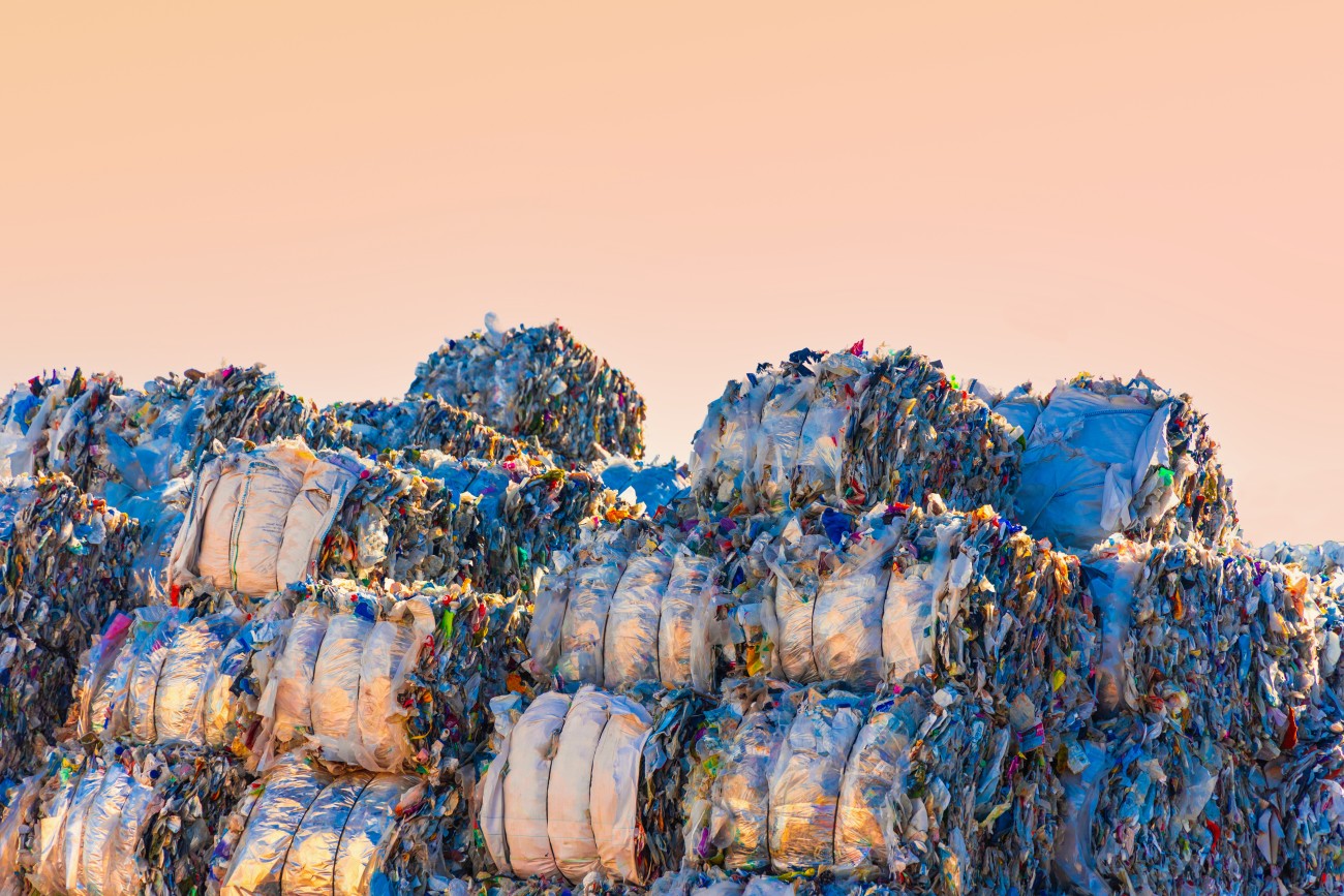 Large group of piles of crushed plastic bales stacking in a recycling plant.