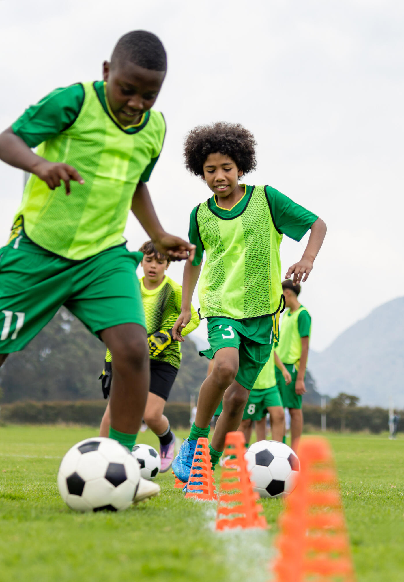 Group of African American kids dribbling the ball during soccer practice - sports training concepts