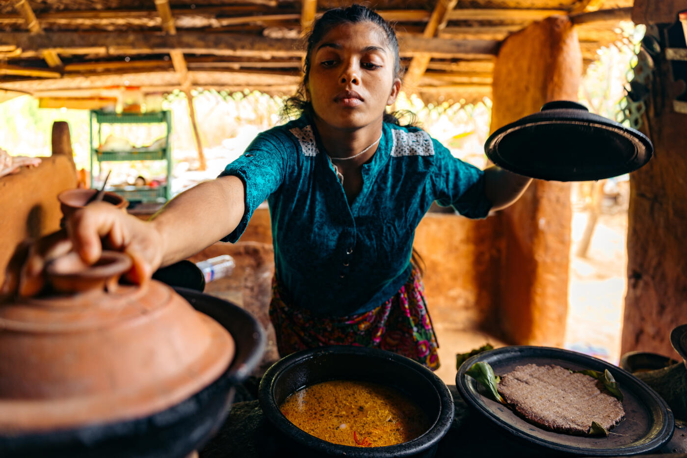 Traditional Sri Lankan home cooking: a local woman prepares authentic village dishes using earthenware pots in a rustic kitchen setting. Fresh spices and natural ingredients bring the flavors of Sri Lanka to life amidst rural charm.