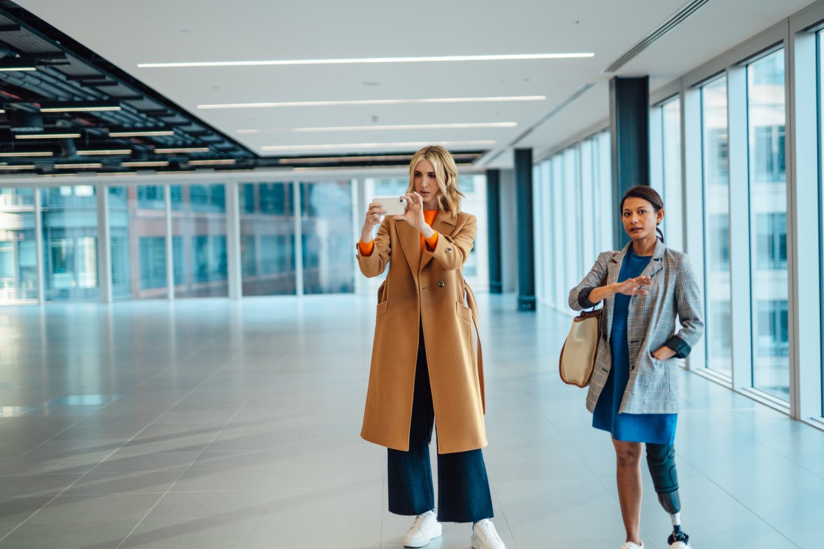 Female estate agent showing client an empty office space via video call. Virtual property viewing. Commercial real estate virtual tour. Diversity, Equity and Inclusion in the workplace.